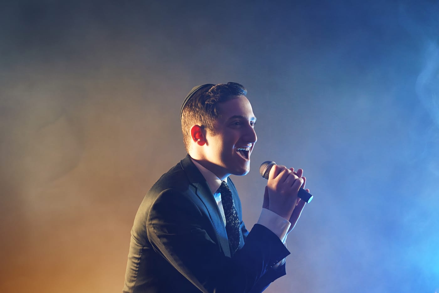 Dovid Pearlman singing on stage under blue and amber light
